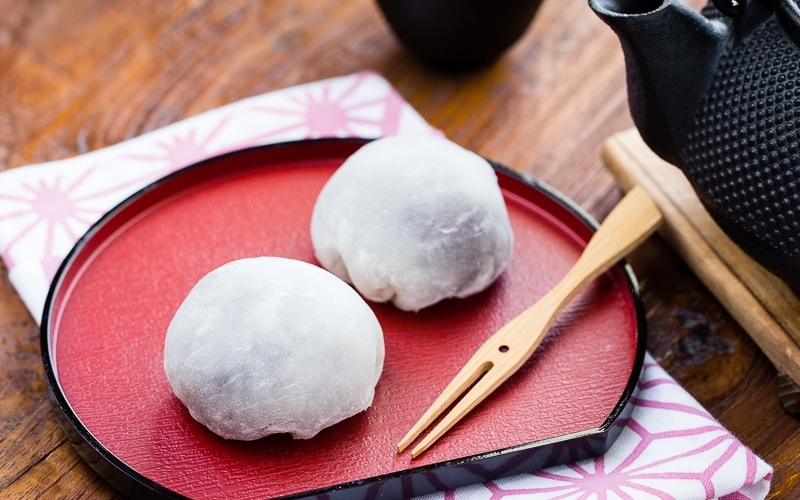 A Japanese red plate containing daifuku mochi.