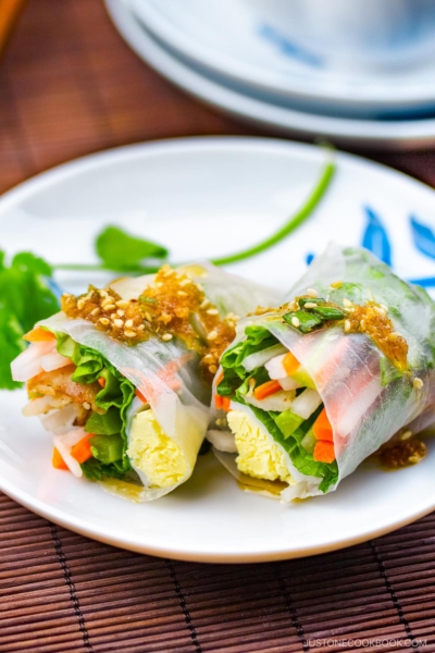 A white plate containing Pork Spring Rolls with Ponzu.
